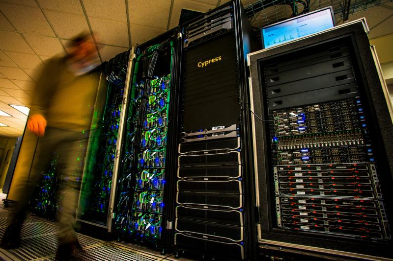 Cypress HPC wall of high processing computers with a blurred image of a person walking in front of them