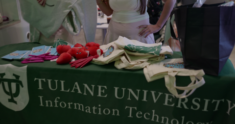 Tulane University Information Technology table with promotional items, including heart stress balls and canvas totes.