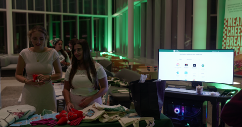 Event booth with two women, a computer display, and green ambient lighting.